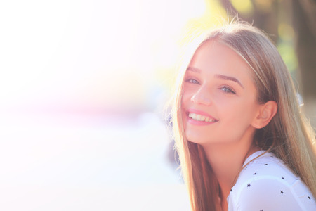 Pretty sexy young woman or girl with long blonde hair in white blouse with stars and cute smiling face in sunny summer dayの写真素材
