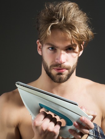 Sexy naked handsome man with messy hair and beard holds white iron on dark backgroundの写真素材