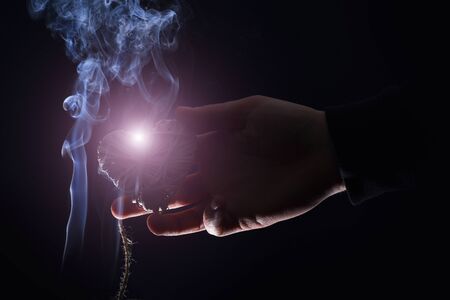 decorative straw heart in male hand as valentines day symbol of love in white smoke on black background, copy spaceの写真素材