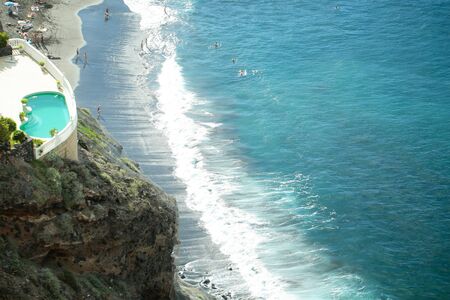 Beautiful sea beach or coast with people bathing and swimming and outdoor pool with blue water from...