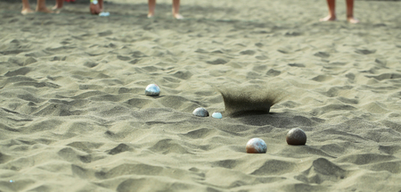 Bocce sport balls, metal and plastic boules, in natural sand on sandy beach outdoors on summer day on blurred grey textured backgroundの写真素材