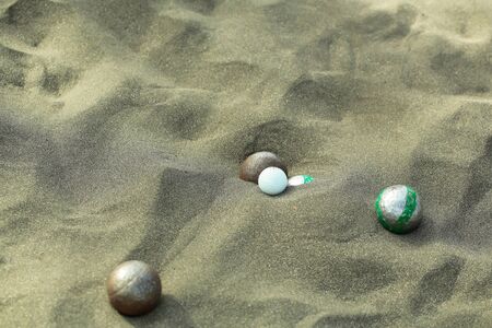 Bocce sport balls, metal and plastic boules, in natural sand on sandy beach outdoors on summer day on grey textured backgroundの写真素材