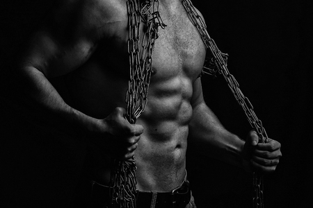 One handsome sexual strong young man with muscular body in blue jeans holding rope with hands hanging on neck and shoulders standing posing in studio black and white, horizontal pictureの写真素材