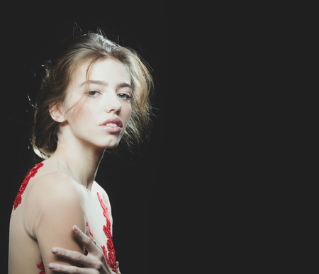 young pretty woman or cute sexy girl with long beautiful blonde hair on adorable face in red embroidered bodysuit on black background, copy spaceの写真素材