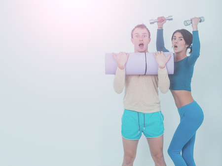 happy couple of pretty woman or cute girl with fitness mat and handsome guy man with muscular torso and sexy body training in sport gym with dumbbells isolated on white background, copy spaceの写真素材