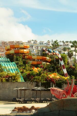 Beautiful water or aqua park with colorful waterslides in resort town with green tropic garden outdoors on summer day on cloudy blue sky backgroundの写真素材
