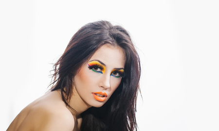 young pretty woman or cute sexy girl with brunette hair, bright fashionable make up on adorable face, has orange lipstick on lips and long eyelashes isolated on white background, copy spaceの写真素材