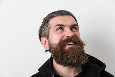 bearded man, long beard, brutal caucasian hipster with moustache on happy smiling face, unshaven guy getting haircut by hairdresser at barbershop in black jacket on white backgroundの写真素材