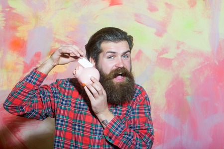 Happy bearded man, caucasian hipster, with long beard and moustache in red plaid shirt putting...
