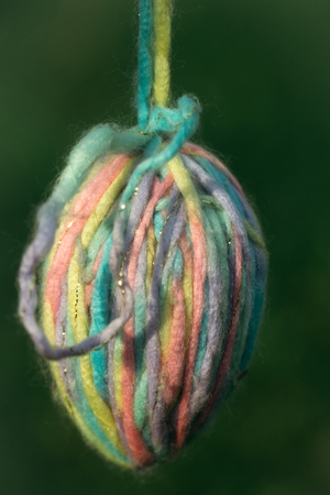 Easter egg made of knitting wool beautiful and colorful on blurred green backgroundの写真素材