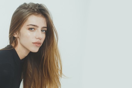 Pretty girl or beautiful woman with long, blond hair, hairstyle, in black sweater posing on white background, copy spaceの写真素材