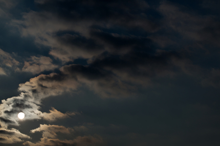 Dramatic night sky with clouds and bright full moon, idyllic moonlight, in dark blue color on overcast backgroundの写真素材