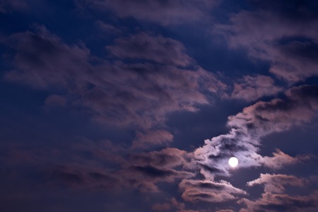 Dramatic night sky with clouds and bright full moon, idyllic moonlight, in dark blue color on overcast backgroundの写真素材