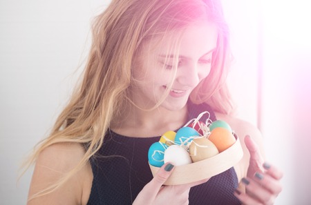 happy easter celebration and decoration. traditional spring holiday food. girl with colorful painted eggs in box, has long blonde hair and smiling cute face on white background.の写真素材