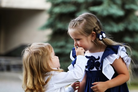 Cute little children, adorable blond baby boy touching nose of small girl with long braid hair on summer day outdoors on natural backgroundの写真素材