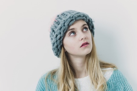 Pretty girl or cute young woman with blond hair and adorable face in fashionable blue sweater and...