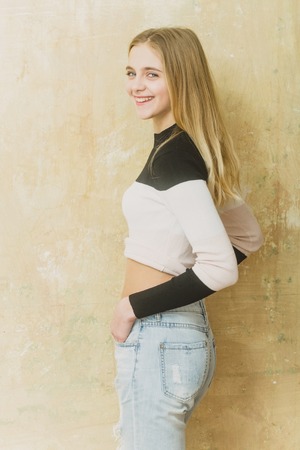 Pretty smiling girl or cute young woman with blond hair and adorable happy face in fashionable black...
