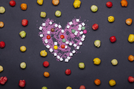 colorful tasty marshmallow, zephyr and dragee, sprinkles sweets in valentines day heart shape on grey backgroundの写真素材
