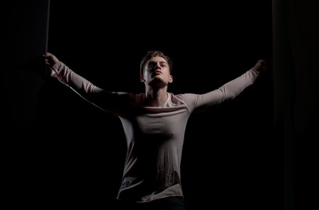 Handsome man or young caucasian macho in grey tshirt with long sleeves, casual wear with stylish haircut, hair posing on black backgroundの写真素材
