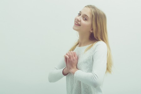 Pretty girl or cute smiling young woman with blond hair and adorable happy face in white sweater, blouse or sweatshirt on grey background, copy spaceの写真素材
