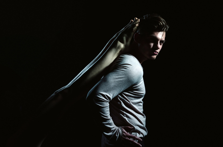 Handsome man or young caucasian macho with stylish haircut, hair, in grey tshirt with long sleeves, casual wear, posing with sexy, female legs on back on black backgroundの写真素材