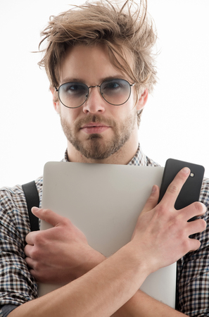 Using technology, internet surfing and video conferencing, Handsome man or male student, businessman, with beard and stylish, blond hair, haircut, in nerd glasses with laptop, computer, and smartphoneの写真素材