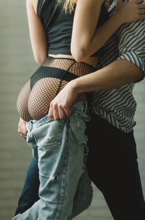 sexy female ass, buttocks, in erotic lingerie, black panties and fishnet tights, pantyhose, muscular male hands undressing blue jeans. Seduction and passionの写真素材