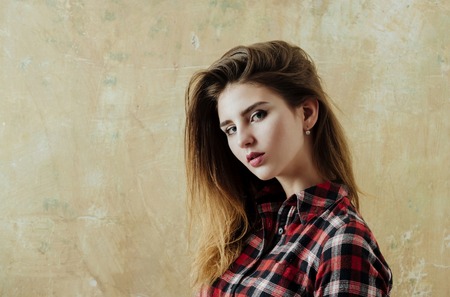 fashion model, with cute make up, makeup on young face, pretty girl or sexy woman has stylish, blond, long hair posing in red plaid shirt on beige wall. Youth and skin care, copy spaceの写真素材