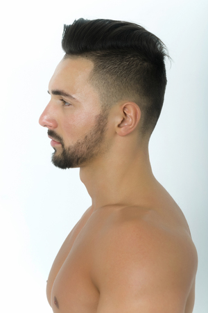 handsome bearded man or sexy fit model with healthy face skin, beard, mustache and stylish hair, haircut, posing in profile on white background. Male beauty and healthの写真素材