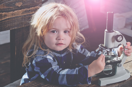 boy student studying at his workplace with microscope, educational concept