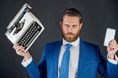 business man in blue suit and tie with typewriter and smartphone or cell phone, businessman with bearded man on grey backgroundの写真素材