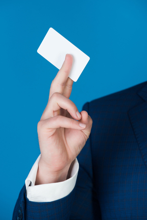 credit or business card in hand of businessman or man in formal outfit on blue background, copy space, business ethicsの写真素材
