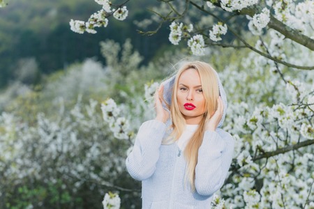 beautiful woman with long blonde hair and red lips on cute face outdoor on floral backgroundの写真素材