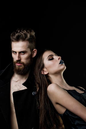 man and woman. couple of bearded man in coat and pretty woman in dress with long hair has fashionable makeup, fashion style people isolated on black background, copy spaceの写真素材