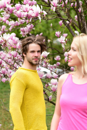 couple in love in spring magnolia flowers, man and happy smiling girl in garden with blossom tree outdoor on natural backgroundの写真素材