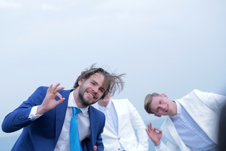 man or happy bearded businessman and twins guys show ok gesture in business formal outfit on light background outdoor, success and meeting, agile businessの写真素材