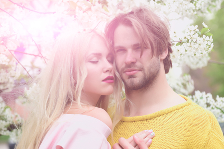 garden with cherry flower in spring or summer nature, man and woman on natural background, couple in love, wedding and fashionの写真素材