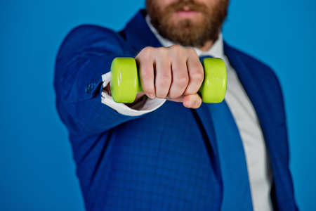 barbell in hand of businessman or bearded man in formal outfit of tie, shirt and jacket on blue background, business successの写真素材