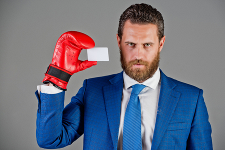 man holding card in blue business suit and red boxing glove on grey background, copy space, business etiquette and ethicsの写真素材