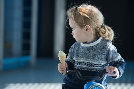 baby or cute small boy with blonde hair eating ice cream in fashionable sweater sunny outdoor,...
