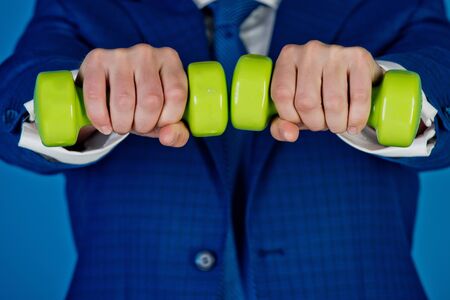 man or businessman with green barbells in hands in formal outfit on blue background, business success, agile businessの写真素材