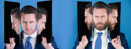 man or serious businessman reflecting in mirror on blue background. Bearded or clean shaven face. Facial hair trend. Skin care. Choice, decision, agile business, archaismの写真素材