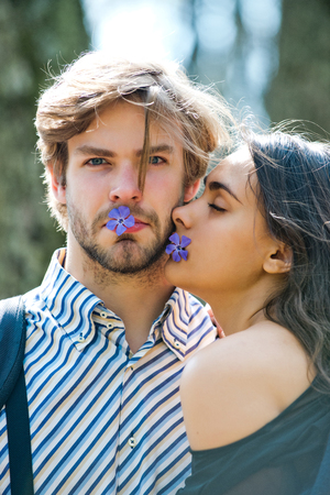 young man with girl sunny outdoor hold flower in mouthの写真素材