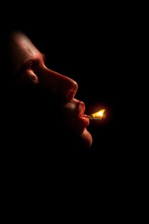 girl or woman with fire on match on black background in dark, copy spaceの写真素材