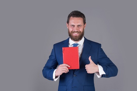 business and success, reading and writing, finance and accounting, happy man with red book and thumb up gestureの写真素材