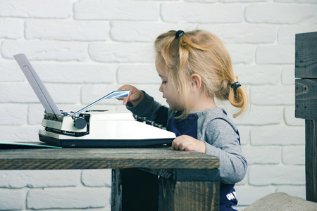boy or small kid with typewriter and paper working at tableの写真素材