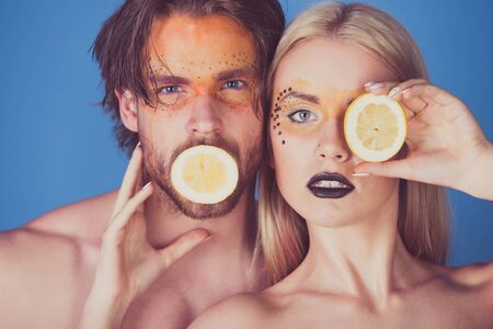man and girl with creative fashionable makeup on face hold lemon fruit on blue background, beauty and fashion, allergy, healthcare and vitamin, vegetarian and dieting, couple in loveの写真素材