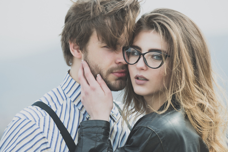 couple in love. girl or woman in stylish glasses with fashion makeup and long hair touching face of handsome, unshaven man with beard. Young couple of lovers on natural background. Love and tendernessの写真素材