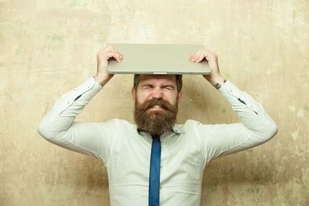 bearded man or hipster with long beard and stylish hair in tie and white shirt hold laptop on...