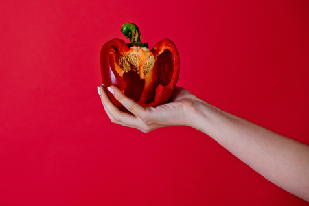 hand of woman hold sweet bell pepper or paprika on red background, healthcare and vitamin, vegetarian and dieting, heartの写真素材